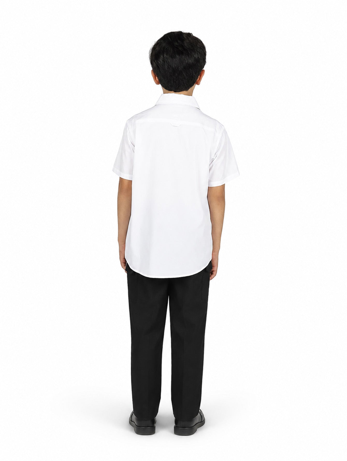 Niño con camisa blanca de manga corta y pantalones negros sobre fondo blanco.