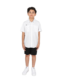 Niño con camisa blanca de manga corta y pantalones negros sobre fondo blanco.