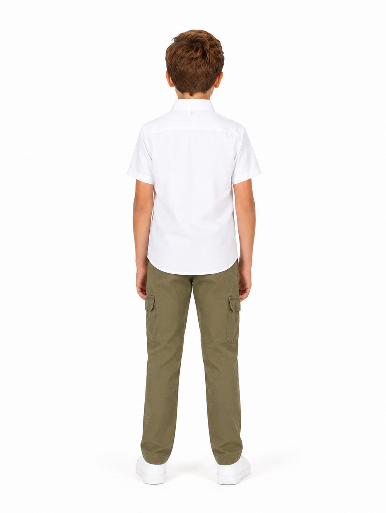 Niño modelando una camisa blanca de manga corta con bolsillos y pantalones cargo color verde oliva.