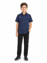 Niño vistiendo una camisa casual color navy de manga corta con bolsillos frontales y pantalones negros.