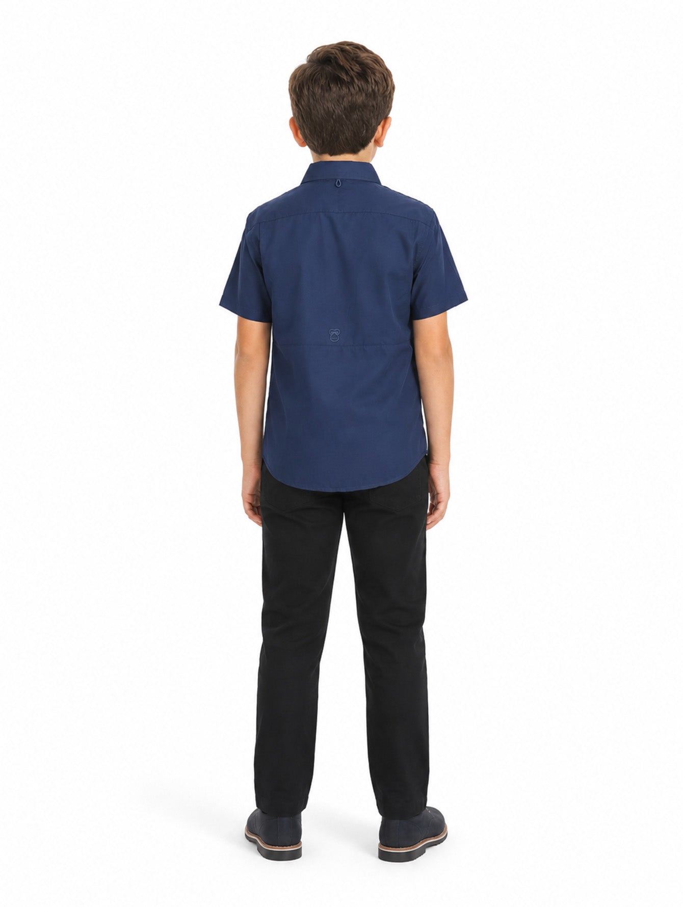 Niño vistiendo una camisa casual color navy de manga corta con bolsillos frontales y pantalones negros.