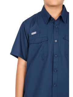 Niño vistiendo una camisa casual color navy de manga corta con bolsillos frontales y pantalones negros.