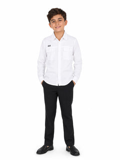 Niño vistiendo una camisa blanca de manga larga y pantalones negros sobre fondo blanco.