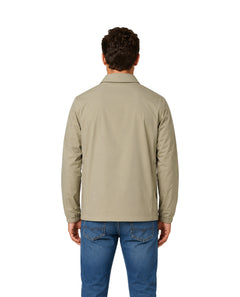 Hombre vistiendo una camisa color beige de manga larga con botones y pantalones azules.