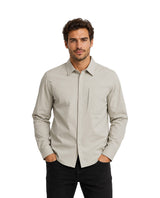 Hombre vistiendo una camisa de manga larga color gris claro con cuello y un bolsillo en el pecho.