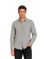 Hombre vistiendo una camisa gris de manga larga con botones y pantalones negros.